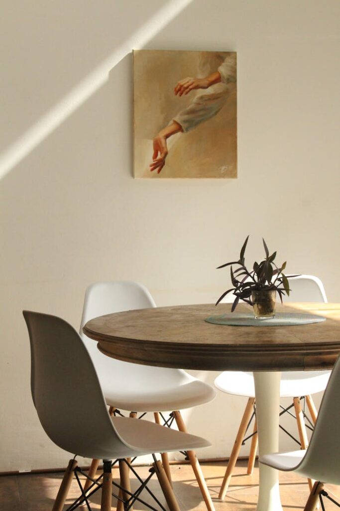 pexels photo 2995012 Sunlit minimalist dining room with round table, chairs, and painting.